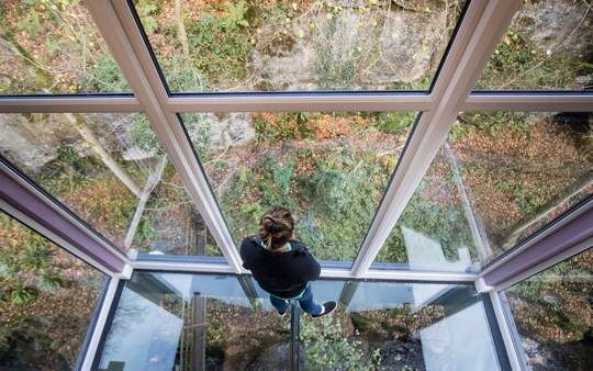 دختری ایستاده روی سقف شیشه ای ساختمانی با چشم  اندازی زیبا در یورکشایر انگلیس 