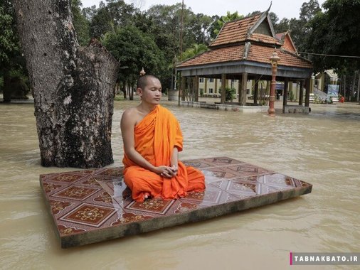 کامبوج: راهب بودایی در حال تأمل روی قطعه ای به جا مانده از یک خانه در استان سیل زده پنوم پن