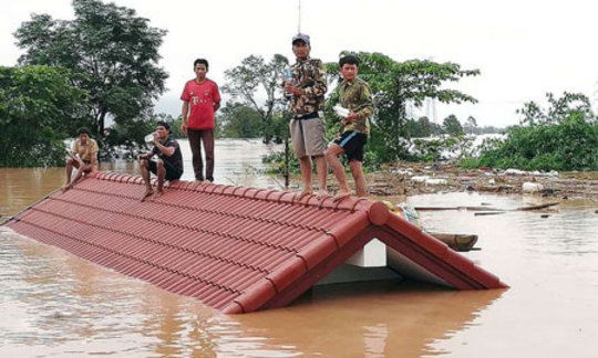 مردم ایستاده روی بام یک خانه پس از شکستن یک سد و جاری شدن سیل در لائوس