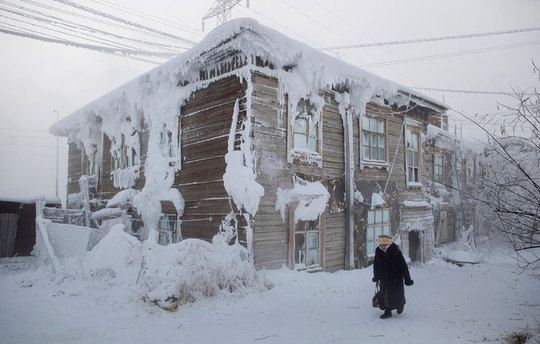 عبور یک زن از کنار یک خانه یخ زده در مرکز روستا