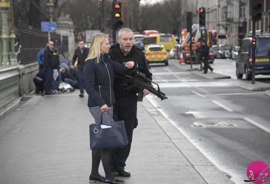 یک پلیس مسلح در حال کمک‌رسانی به یک زن پس از وقوع حادثه در پل وستمینیستر بریج شهر لندن