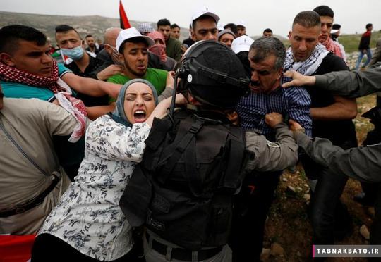 تلاش فلسطینیان برای جلوگیری از بازداشت یک معترض توسط نظامیان رژیم صهیونیستی در حرکت اعتراضی در روز زمین در کرانه باختری.