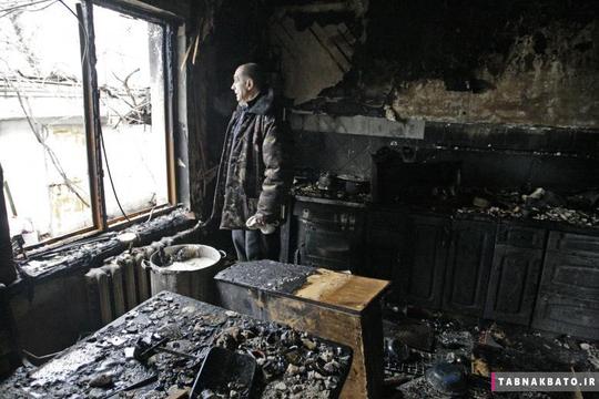 یک ساکن محلی در شهر دونتسک اوکراین به بیرون خیره شده است و خانه‌ی گلوله باران شده‌ی خود را نظاره می‌کند.