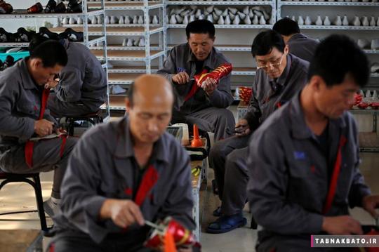 کارگران اهل کشور کره شمالی در حال تولید کفش ورزشی در یک کارخانه‌ی موقت در روستایی در اطراف شهر داندونگ