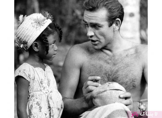شان کانری در حال امضا دادن بر روی یک نارگیل، برای هوادار کوچک جامائیکایی در طول فیلمبرداری فیلم سینمایی دکتر نو،  سال ۱۹۶۲ میلادی