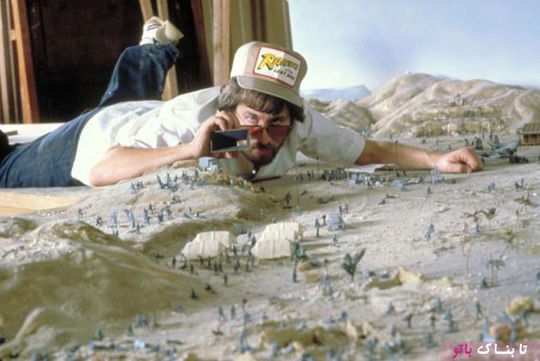 استیون اسپیلبرگ در حال عکسبرداری از ماکتی که برای اولین بخش از فیلم ایندیانا جونز ساخته شده است در سال ۱۹۸۰ میلادی