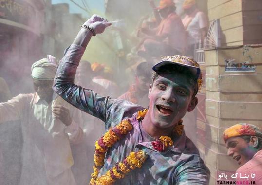 مردی در حال پاشیدن پودر‌های رنگی در حین برگزاری جشن هولی در شهر بارسانا در ایالت اوتار پرادش هند