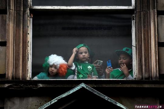 بچه‌ها در حال تماشای راهپیمایی روز سنت پاتریک از پشت یک پنجره در شهر دوبلین