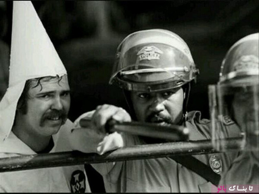 محافظت پلیس سیاه پوست از یک مرد عضو گروه کو کلاکس کلان در سال ۱۹۸۳، این گروه عقیده داشتند که افراد سفید پوست بر دیگران برتری دارند